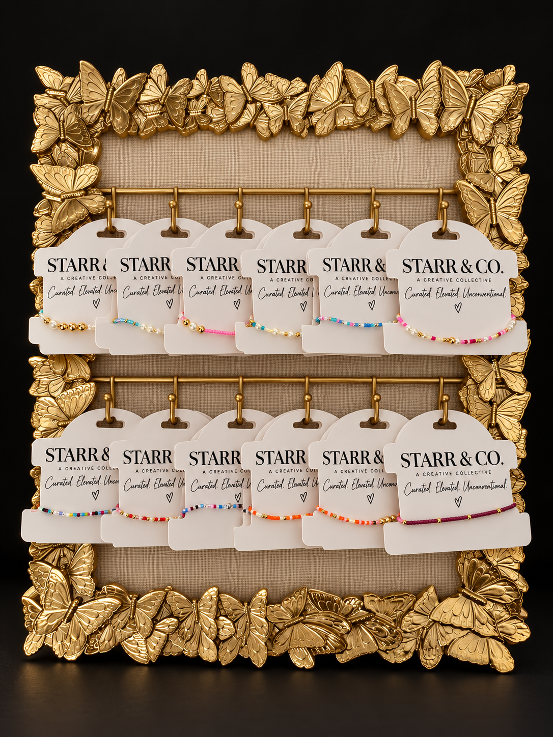 STARR & CO. colorful bracelets displayed in an ornate gold butterfly frame